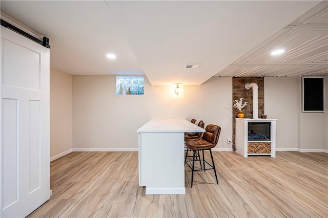 bar featuring a barn door and light hardwood / wood-style flooring