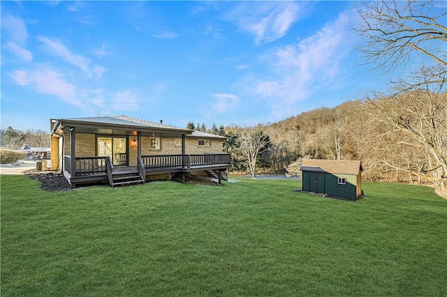 rear view of property with a yard, a deck, and a storage shed