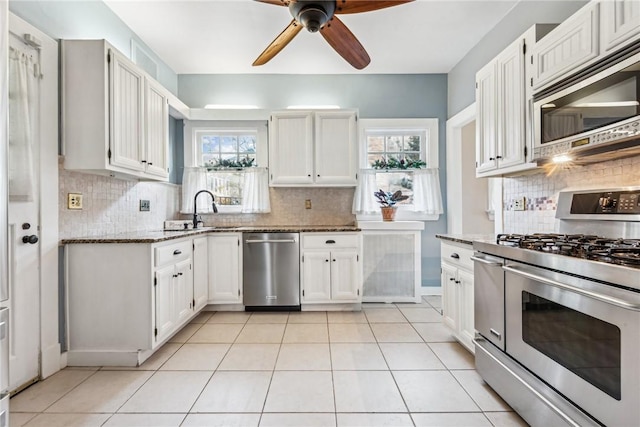 kitchen with decorative backsplash, stainless steel appliances, sink, stone countertops, and white cabinetry