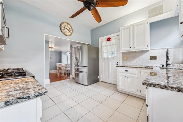 kitchen with light stone countertops, stainless steel fridge, white cabinetry, and ceiling fan