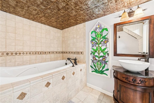 bathroom with tiled tub, tile patterned flooring, and vanity