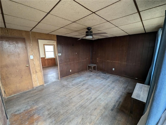 empty room featuring wood-type flooring, ceiling fan, and wood walls