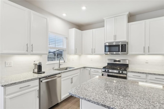 kitchen featuring white cabinets, stainless steel appliances, light stone countertops, and sink