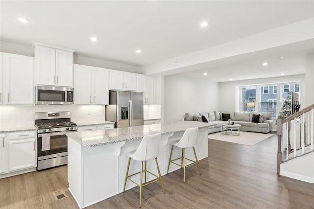 kitchen featuring white cabinetry, light hardwood / wood-style flooring, a breakfast bar, a kitchen island, and appliances with stainless steel finishes