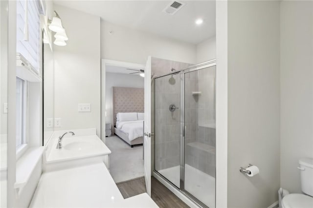 bathroom with ceiling fan, hardwood / wood-style floors, toilet, vanity, and a shower with shower door