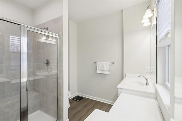 bathroom featuring toilet, vanity, a shower with shower door, and hardwood / wood-style flooring