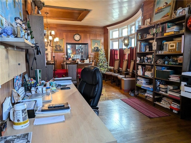 home office featuring wood walls, wood-type flooring, and an inviting chandelier