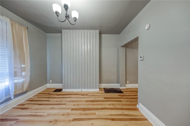 unfurnished dining area featuring light hardwood / wood-style flooring and an inviting chandelier