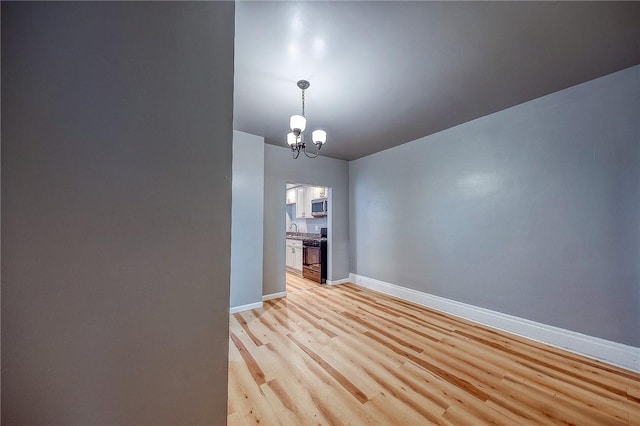 empty room with light wood-type flooring, sink, and an inviting chandelier