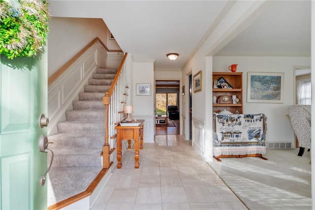 entryway featuring crown molding and light tile patterned flooring