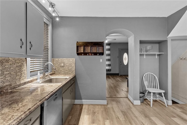 kitchen featuring ceiling fan, sink, stainless steel dishwasher, backsplash, and light hardwood / wood-style floors