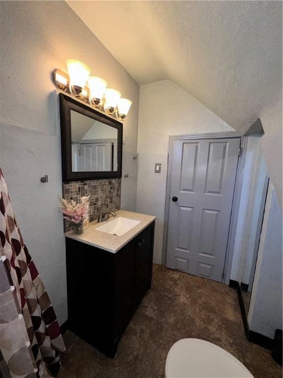 bathroom featuring a textured ceiling, vaulted ceiling, decorative backsplash, toilet, and vanity