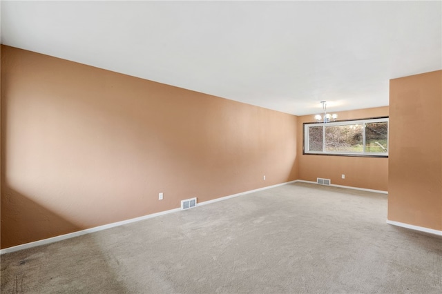 spare room featuring carpet floors and a chandelier