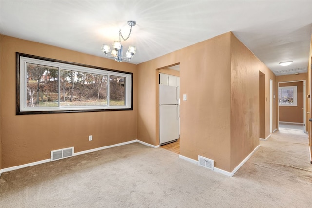 carpeted spare room featuring a notable chandelier