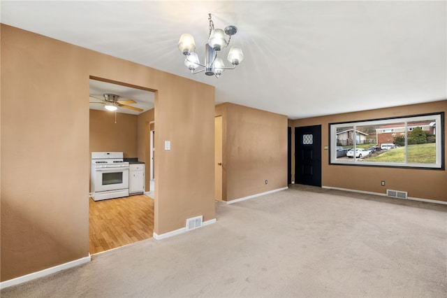 spare room with carpet flooring and ceiling fan with notable chandelier