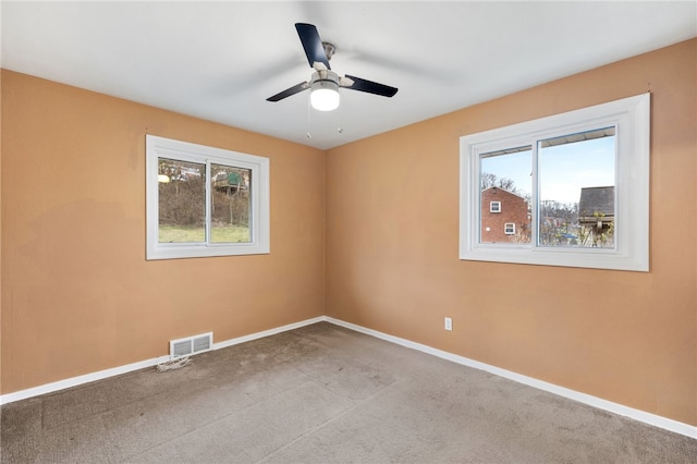 empty room featuring ceiling fan, light carpet, and a wealth of natural light