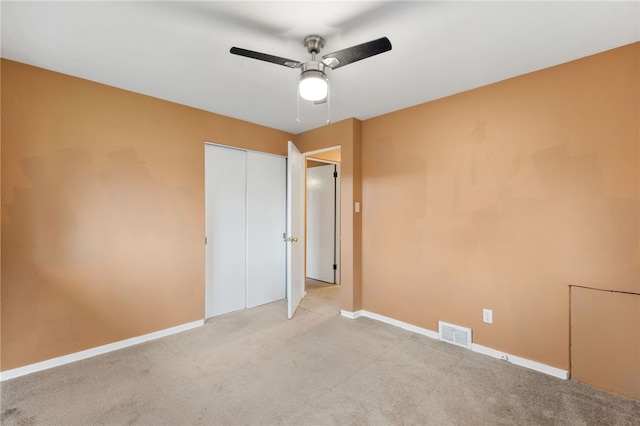 unfurnished bedroom featuring ceiling fan, light colored carpet, and a closet