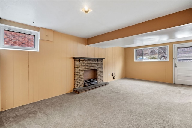 unfurnished living room featuring a fireplace, carpet floors, and wooden walls