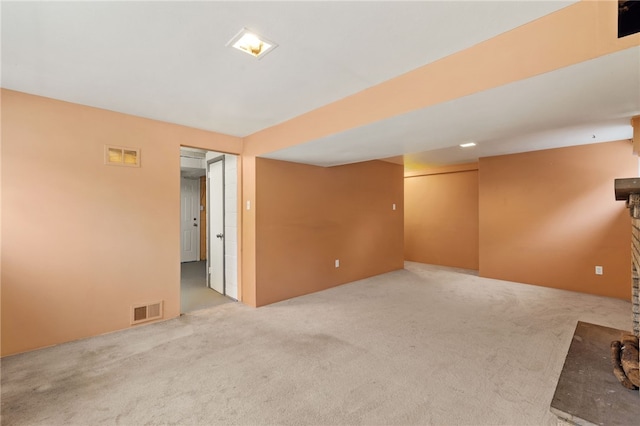 empty room with a fireplace and light colored carpet