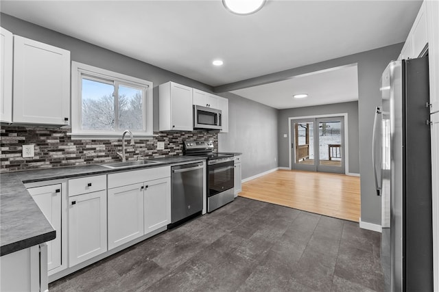 kitchen with white cabinets, decorative backsplash, sink, and stainless steel appliances