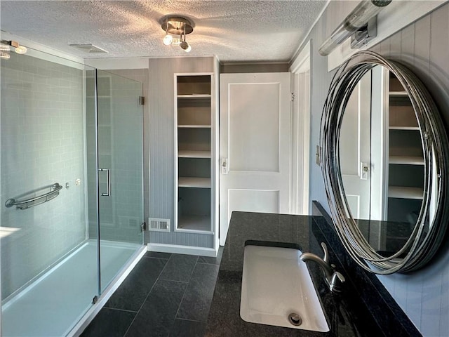 bathroom featuring a textured ceiling, vanity, and an enclosed shower