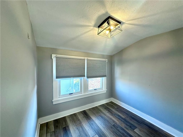 unfurnished room with a textured ceiling, dark hardwood / wood-style flooring, and vaulted ceiling