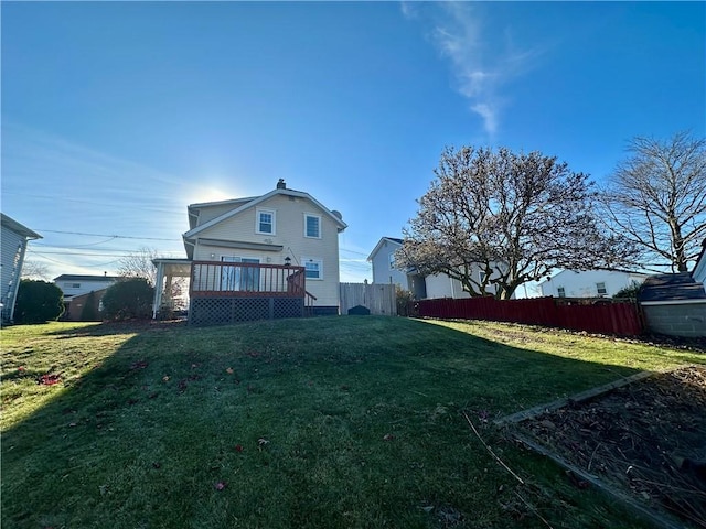 back of property featuring a wooden deck and a lawn