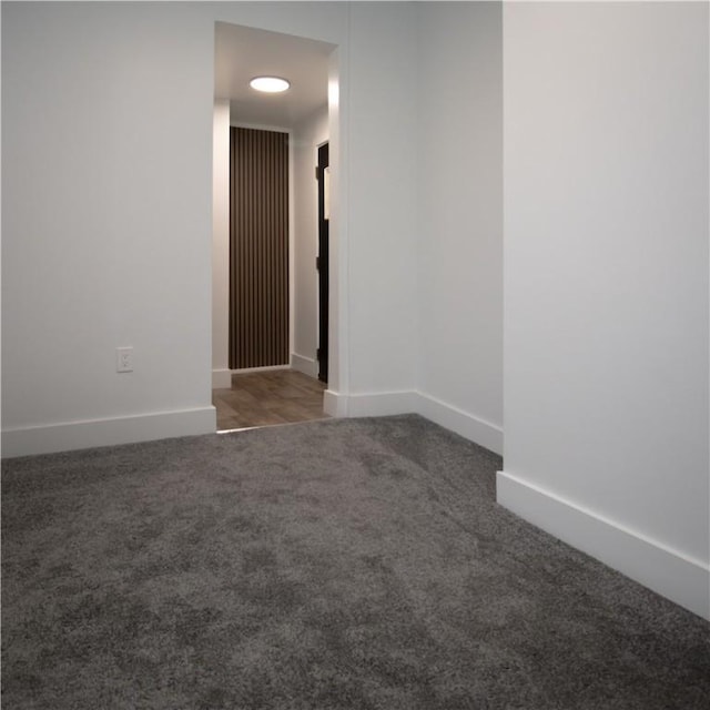 unfurnished room with dark colored carpet