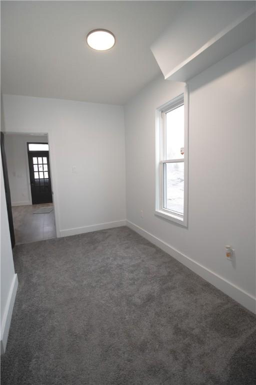 spare room featuring dark colored carpet