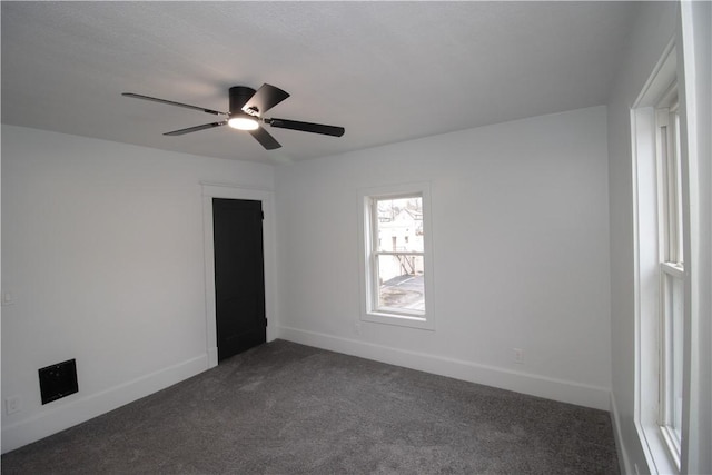 empty room with dark colored carpet and ceiling fan