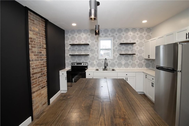 kitchen with sink, white cabinetry, decorative light fixtures, stainless steel fridge, and electric stove