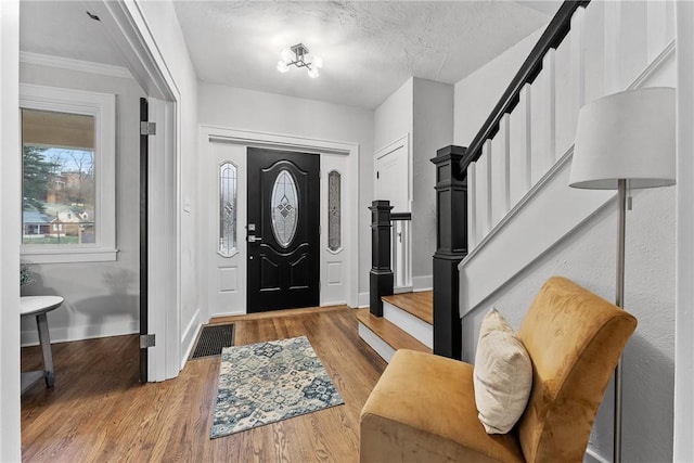 entrance foyer featuring hardwood / wood-style floors, a textured ceiling, and crown molding