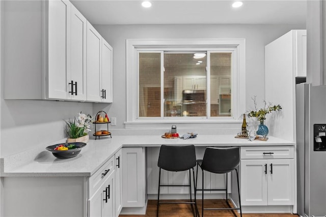 kitchen with white cabinets, light stone countertops, and stainless steel refrigerator with ice dispenser