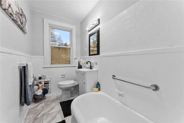 bathroom with a tub, crown molding, vanity, and toilet