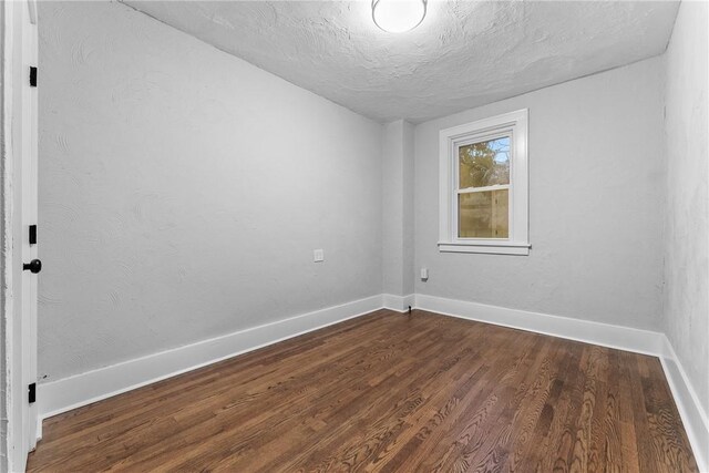 spare room with a textured ceiling and dark hardwood / wood-style floors