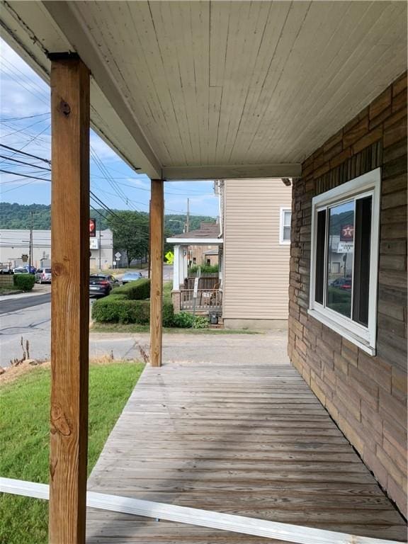 wooden deck with a lawn and covered porch