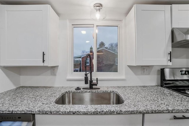 kitchen with light stone counters, white cabinetry, and sink