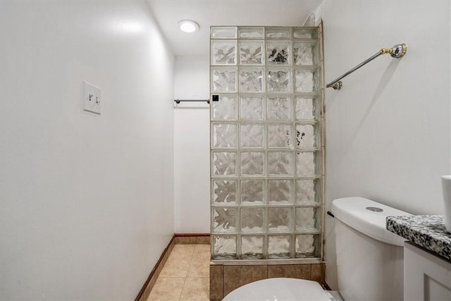 bathroom featuring tile patterned flooring, vanity, toilet, and walk in shower