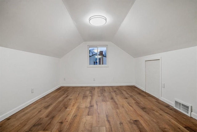 additional living space with wood-type flooring and vaulted ceiling