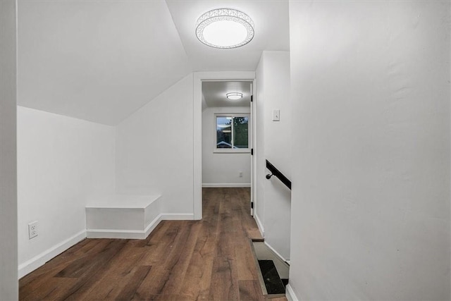 hallway with lofted ceiling and dark wood-type flooring