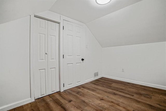 additional living space featuring vaulted ceiling and dark wood-type flooring