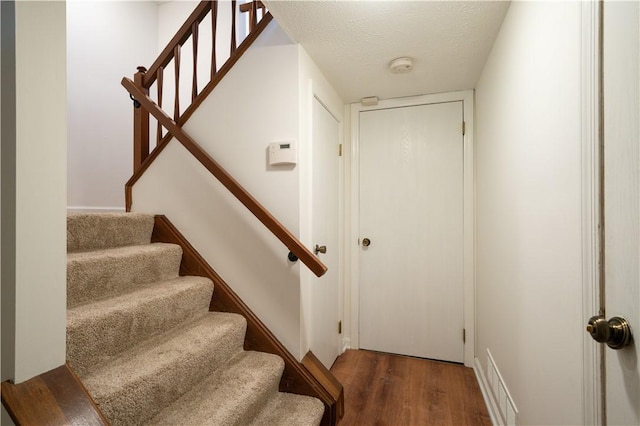 staircase with hardwood / wood-style floors and a textured ceiling