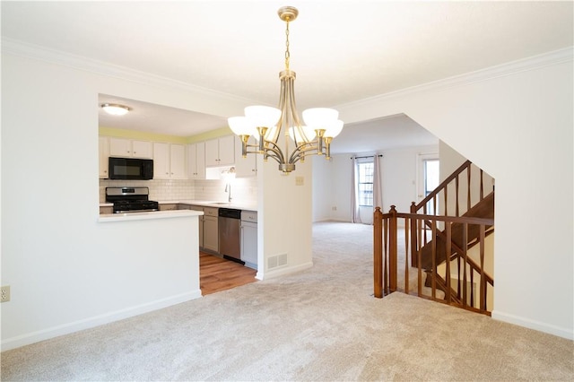 kitchen featuring white cabinets, light colored carpet, hanging light fixtures, and appliances with stainless steel finishes