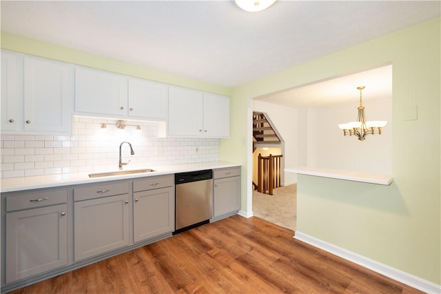 kitchen featuring stainless steel dishwasher, gray cabinetry, sink, decorative light fixtures, and an inviting chandelier