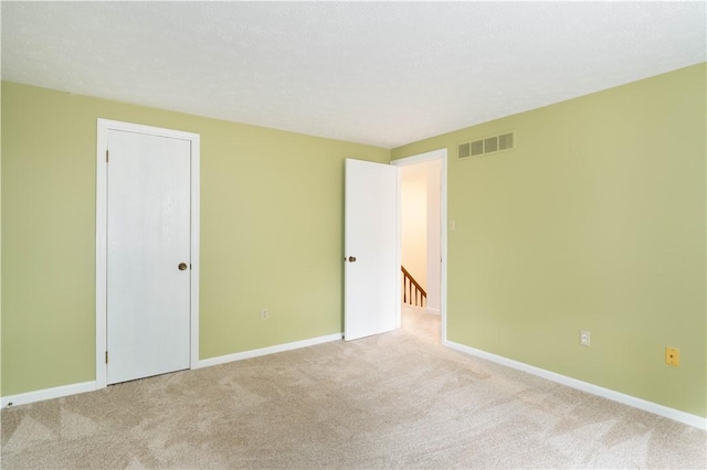 empty room featuring light carpet and a textured ceiling