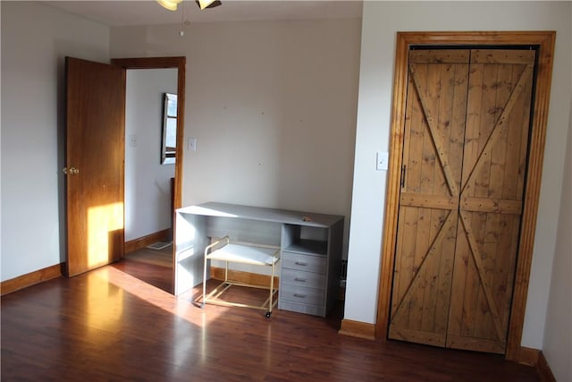 unfurnished bedroom with ceiling fan and dark wood-type flooring