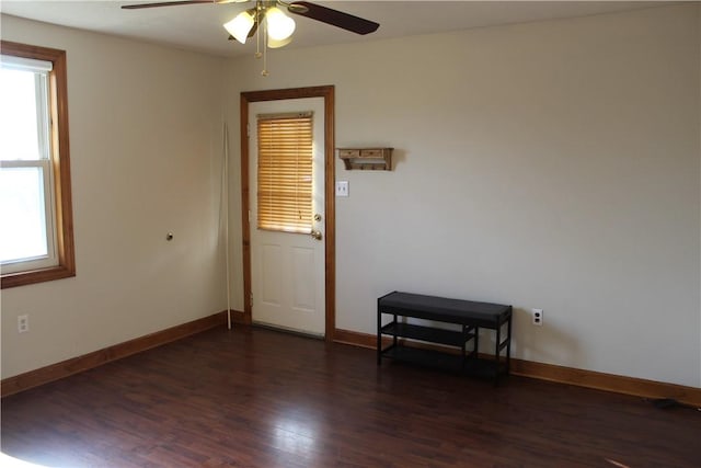 spare room featuring a wealth of natural light, ceiling fan, and dark hardwood / wood-style floors