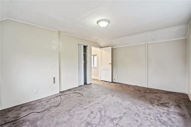 spare room featuring light colored carpet and vaulted ceiling