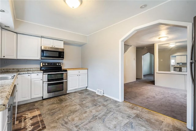 kitchen with white cabinets, light carpet, stainless steel appliances, and sink