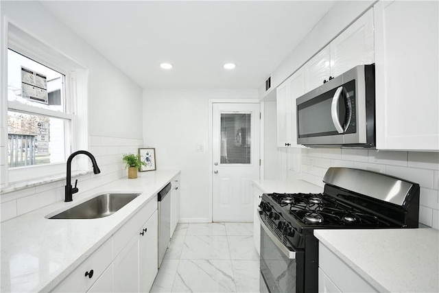 kitchen with tasteful backsplash, light stone countertops, white cabinets, and stainless steel appliances